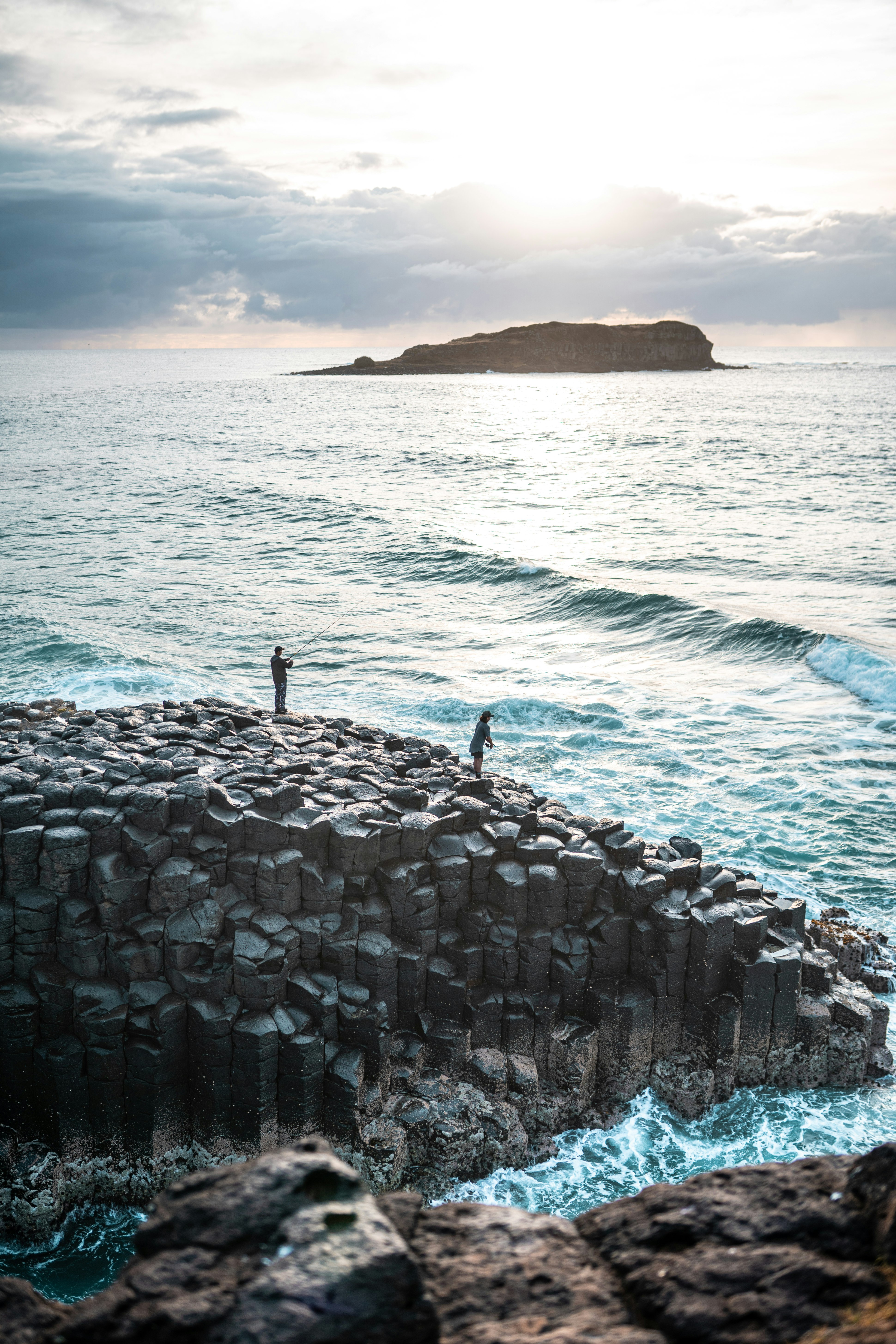 person standing on rock formation near sea during daytime